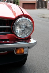 Rundr Scheinwerfer eines englischen Roadster und Sportwagen der Siebzigerjahre in Rot im Sommer...
