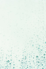 Rain drops on grey background  on rainy day on outside window glass. Beautiful view of grey sky backdrop. Water drops on glass with blurred edges.