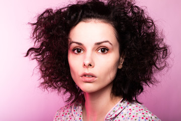 beautiful curly girl in pajamas, pink background