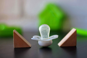 White pacifier next to some toys.