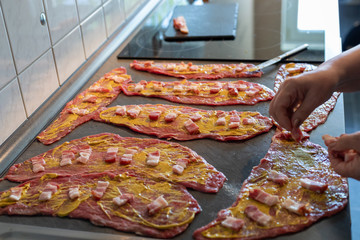 preparing beef rouladen, fresh raw meat coated with mustard and onions