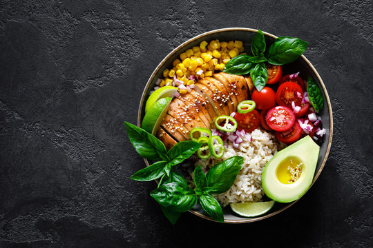Grilled chicken breast lunch bowl with fresh tomato, avocado, corn, red onion, rice and basil