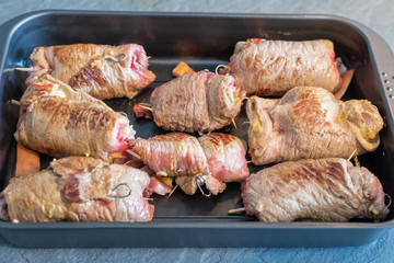 beef roulades, german stuffed meat rolls roast in a pan on the black stove