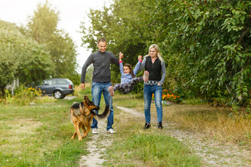 Naklejka na ściany i meble Happy children and parents with dog as family running in the nature