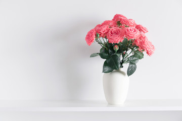 Beautiful flowers, pink roses. Roses in vase on shelf against white wall. Valentines Day, Easter, Happy Women's Day, Mother's day. Space for text.