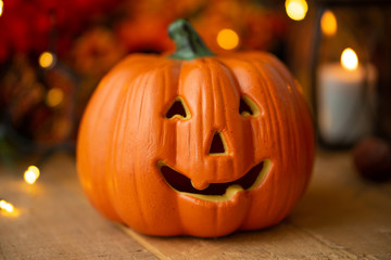 Fototapeta premium Halloween pumpkin with leaves on an old wooden table with luminous lights and an old lamp. Autumn mood and atmospheric photo