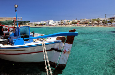 Fototapeta na wymiar Greek fishing boat in clear Aegean Sea overlooking Agia Anna Beach, Naxos, Greek Islands