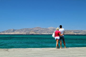 Fototapeta na wymiar Couple hugging, looking out to sea and towards Paros Island from Naxos, Greek Islands