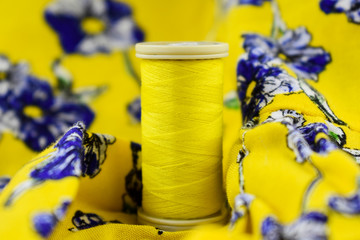 sewing thread. yellow color. with yellow flowers on fabric. yellow fabric background