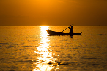 Fototapeta na wymiar dugout canoe fishermen silhouette against orange sunrise on Lake Malawi, the sun glitter on the Lake, South-East-Africa