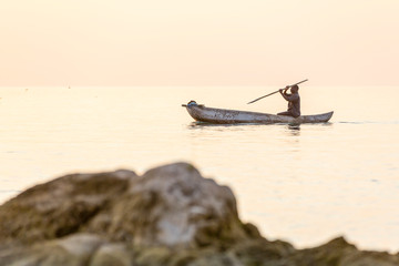 dugout canoe fishermen silhouette against orange sunrise on Lake Malawi, the sun glitter on the...