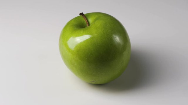 Rotating green apple on white background