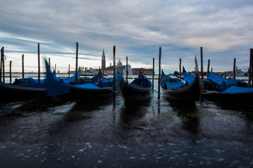 Gondolas in Venice at dusk taken on the shoreline besides the Piazza San Marco / St Marks Square.The image was taken during a dramatic sunset.