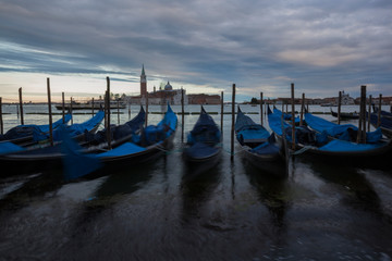 Fototapeta na wymiar Gondolas in Venice at dusk taken on the shoreline besides the Piazza San Marco / St Marks Square.The image was taken during a dramatic sunset.