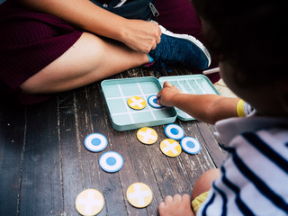 Little boy playing noughts and crosses on a wooden bench