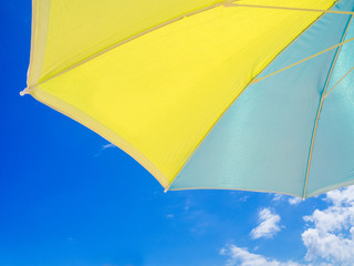 blue and yellow parasol seen from below with the sky behind