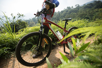 Naklejka na ściany i meble Cross country biking woman cyclist with mountain bike on tropical rainforest trail