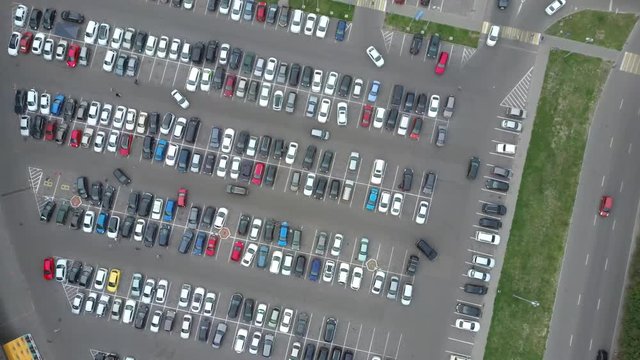 A view from above to the process of car parking. Heavy traffic in the parking lot. Searching for spaces in the busy car park. Parking advice. Cruising for parking in busy business center