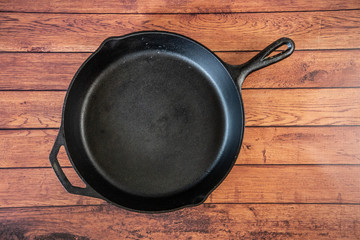 Cast iron skillet on wooden surface - top view with copy space