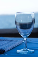 serving table with glass and napkin are against the blue sea
