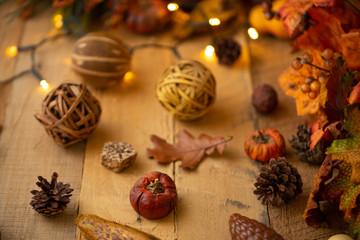 Autumn composition with leaves and elements of decor on an old wooden table with luminous lights and an old lamp. Autumn mood, and atmospheric photo. Horizontal photo, flat lay with space