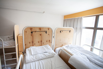 View of hostel room and two-level beds with linens and fresh sheets. Home for travelers and backpackers to spend the night. Cheep hotel. Interior of guesthouse or dormitory.