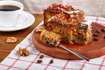 a piece of cake with caramel cream cutted with spoon on a wooden kitchen board, brown wooden background..