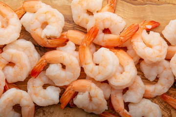 Background of shrimp, macro. Sea food, wholesome and tasty food. On a wooden background. Background for cooking, menu, selling seafood