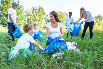 Volunteers with garbage bags cleaning up garbage outdoors - ecology concept..