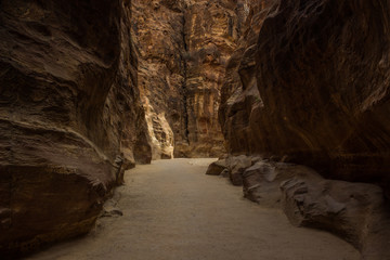canyon narrow dark path way between steep rocky natural walls, Middle East heritage touristic site for walking and sightseeing in wilderness environment 