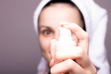 beautiful girl in a towel on the head in hand holding a cream