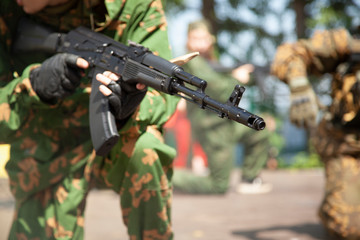 A guy with a gun in his hands. A man in uniform with a firearm. The barrel of a machine gun for shooting. A guy in the army serves his military command.