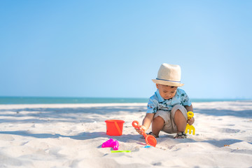 Fototapeta na wymiar Asian two year old toddler boy playing with beach toys on beach.