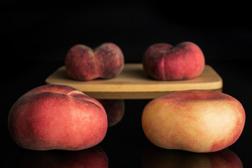 Group of four whole fresh red peach prunus persica platycarpa on bamboo cutting board isolated on...