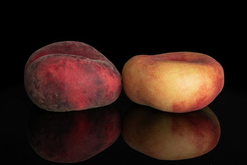Group of two whole fresh red peach prunus persica platycarpa isolated on black glass