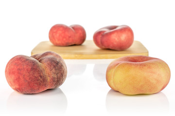 Group of four whole fresh red peach prunus persica platycarpa on bamboo cutting board isolated on...