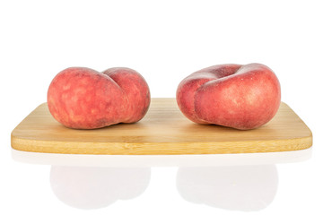 Group of two whole fresh red peach prunus persica platycarpa on bamboo cutting board isolated on white background