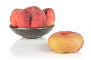 Group of four whole fresh red peach prunus persica platycarpa in dark ceramic bowl isolated on...