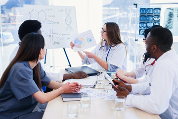 Female doctor holding in hands x ray result on the meeting at modern clinic.. Professional doctors of multi ethnic group examine x ray lungs of patient. Health care concept.