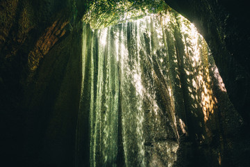 Stream of Tucad Cepung waterfall flowing down in the cave, Bali, Indonesia