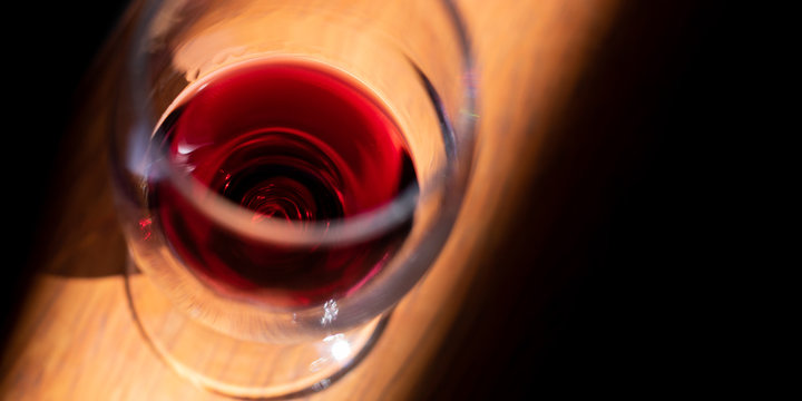 Wineglass with red wine on a wooden table