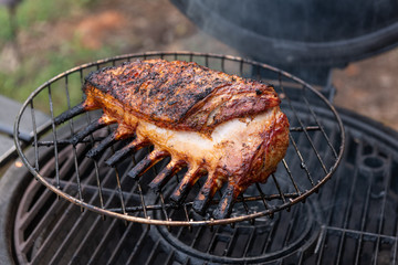 Close-up of a marinated rack of lamb being cooked on an outdoor grill.