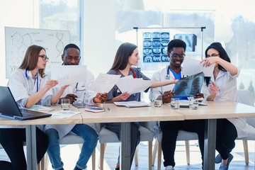 Team of multiethnic doctors having a meeting in conference room in the modern hospital. Group of multiethnic doctors are medical studying studying disease histories patients,