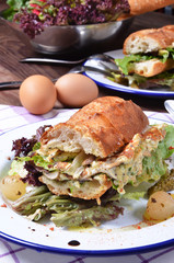 Panini sandwich with truffle mushroom, scrambled eggs and basil on white plate.