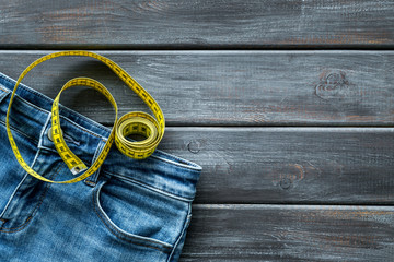 pants and measuring tape for weight loss on wooden background top view copyspace