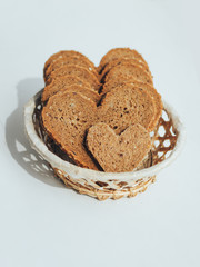 Rye bread in the shape of heart in a straw basket on a white background