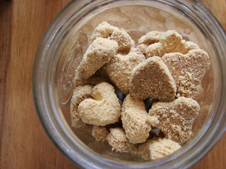 Wooden table with a glass jar full of heart cookies.   