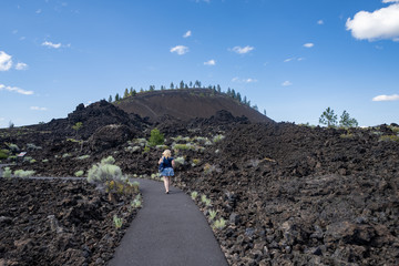 Cute woman takes a hike along the Trail of Molten Lands in Lava Lands Newberry Volcano National Monument in Oregon