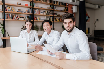 multiracial group of young businessmen in a modern office working with laptop and papers