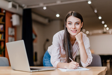 smiling business woman in modern office signing papers and smiling